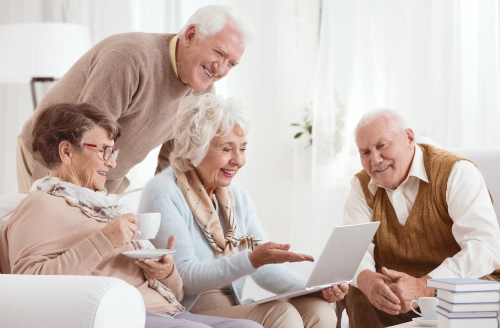 Happy seniors sitting together looking at laptop screen
