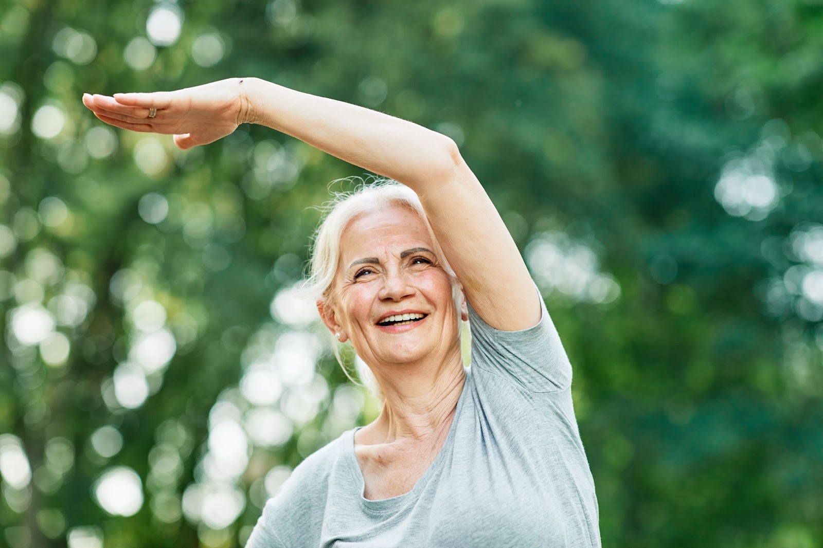 an older woman is stretching before her workout to help with preventing injuries as a senior.