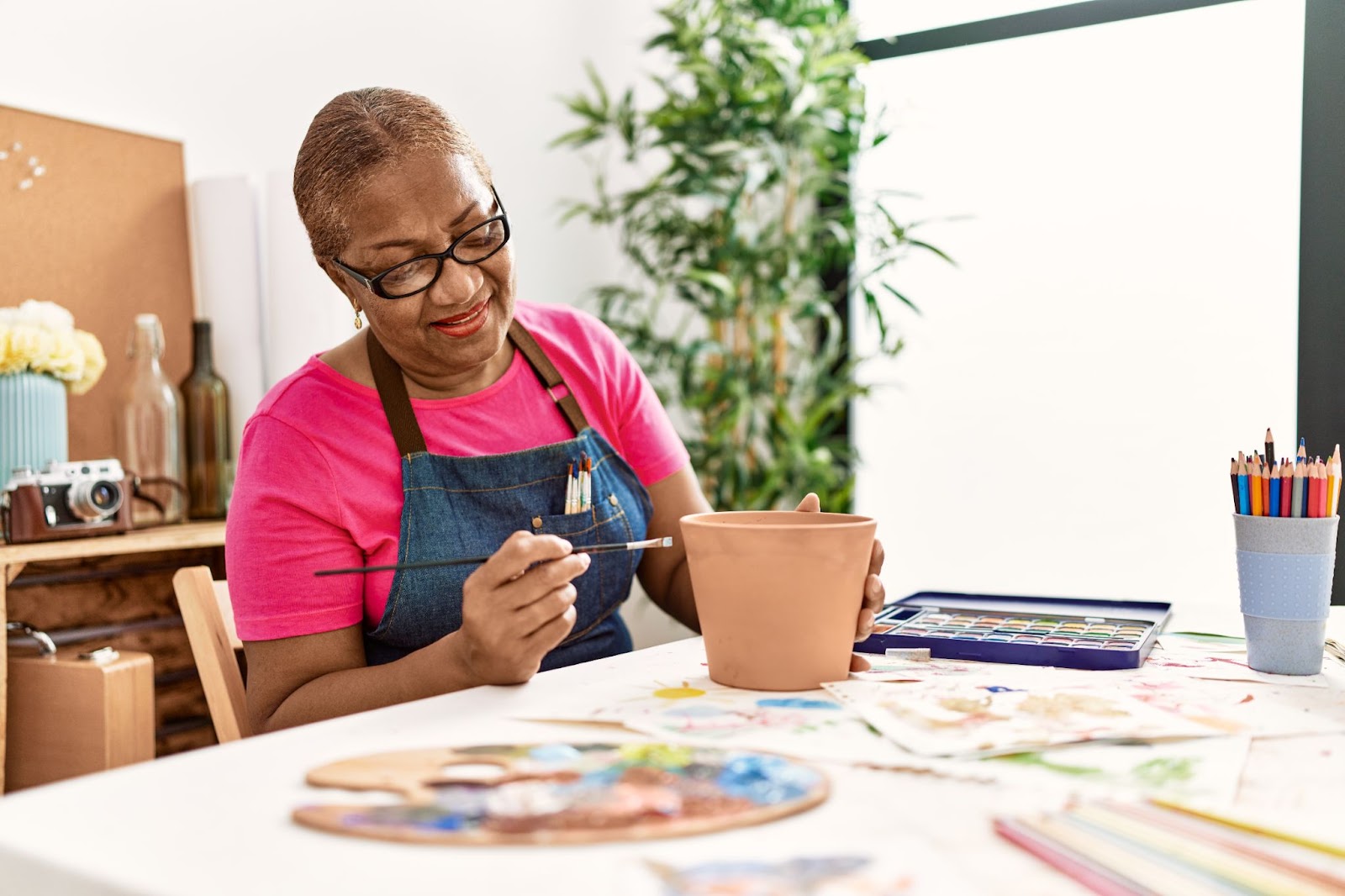 A smiling senior paints a brown flower pot.