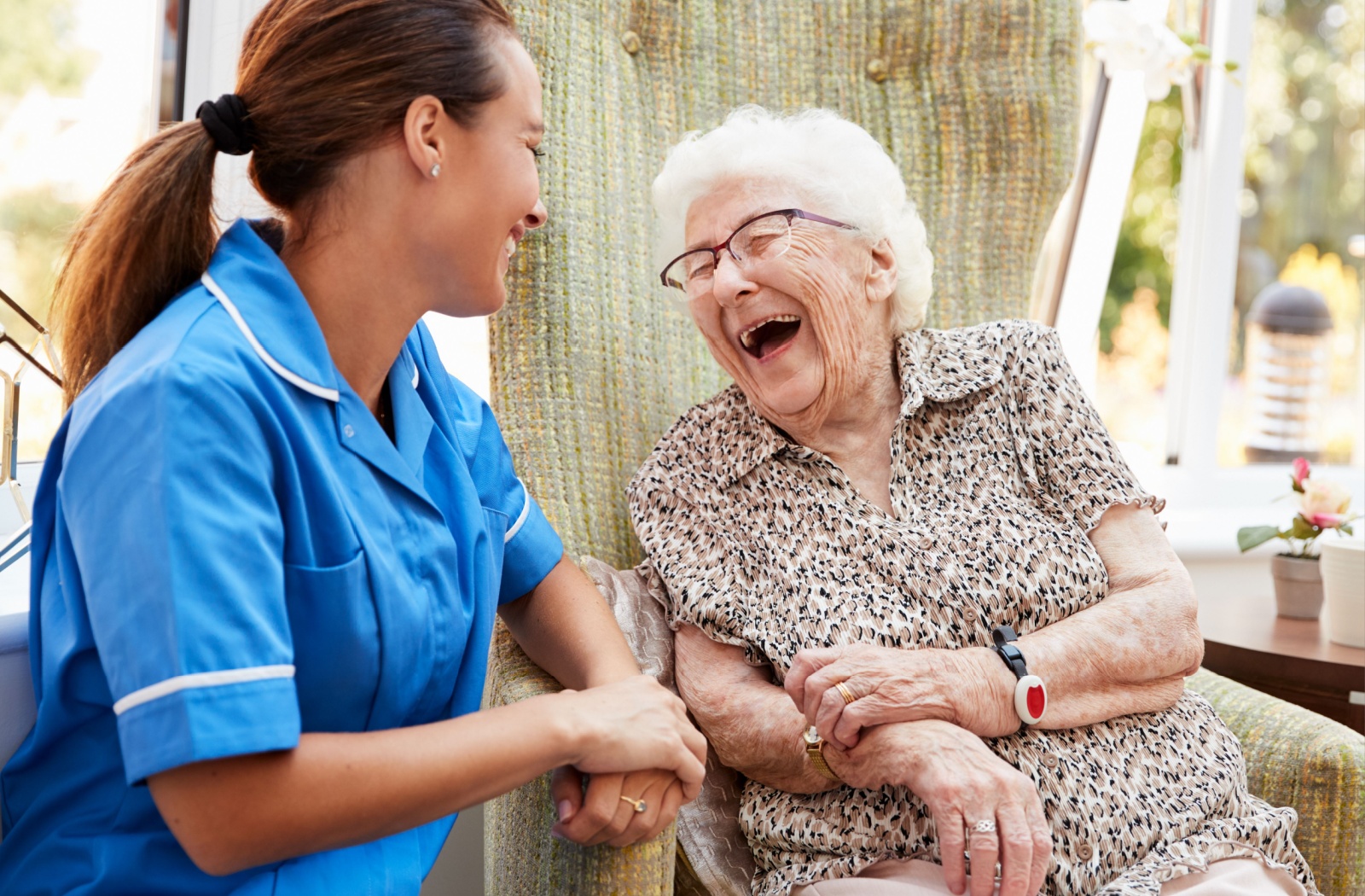 An assisted living resident shares a laugh with a nurse.