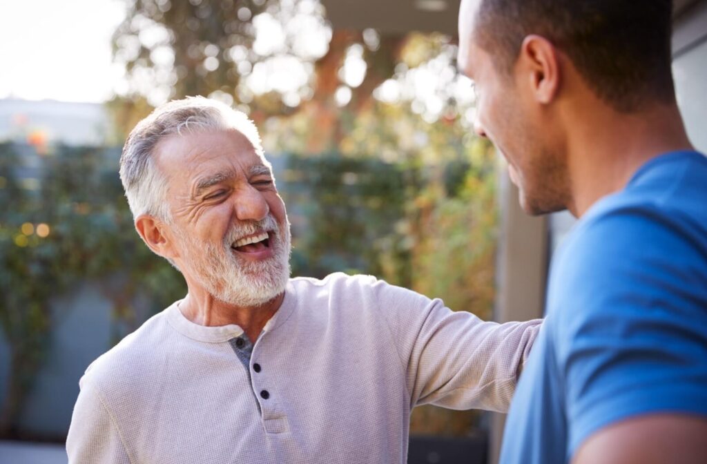 Smiling older adult talking with a younger person outdoors highlighting connection and support in assisted living conversations