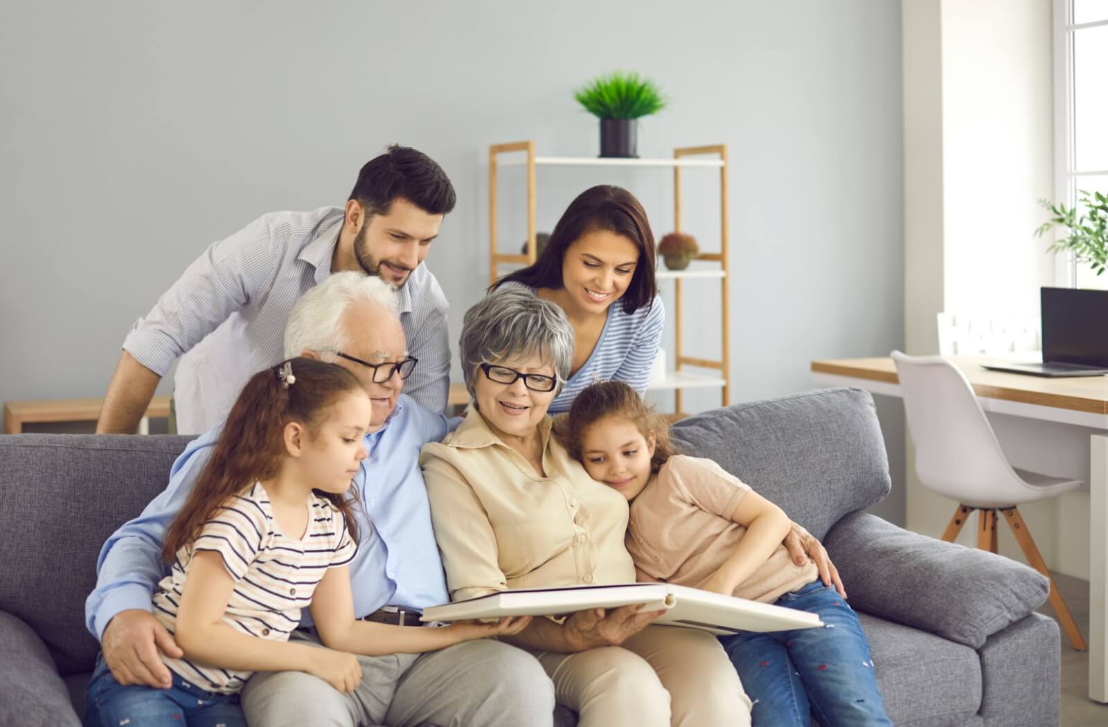 A senior couple in memory care gathers on a couch with their family, enjoying a photo album.