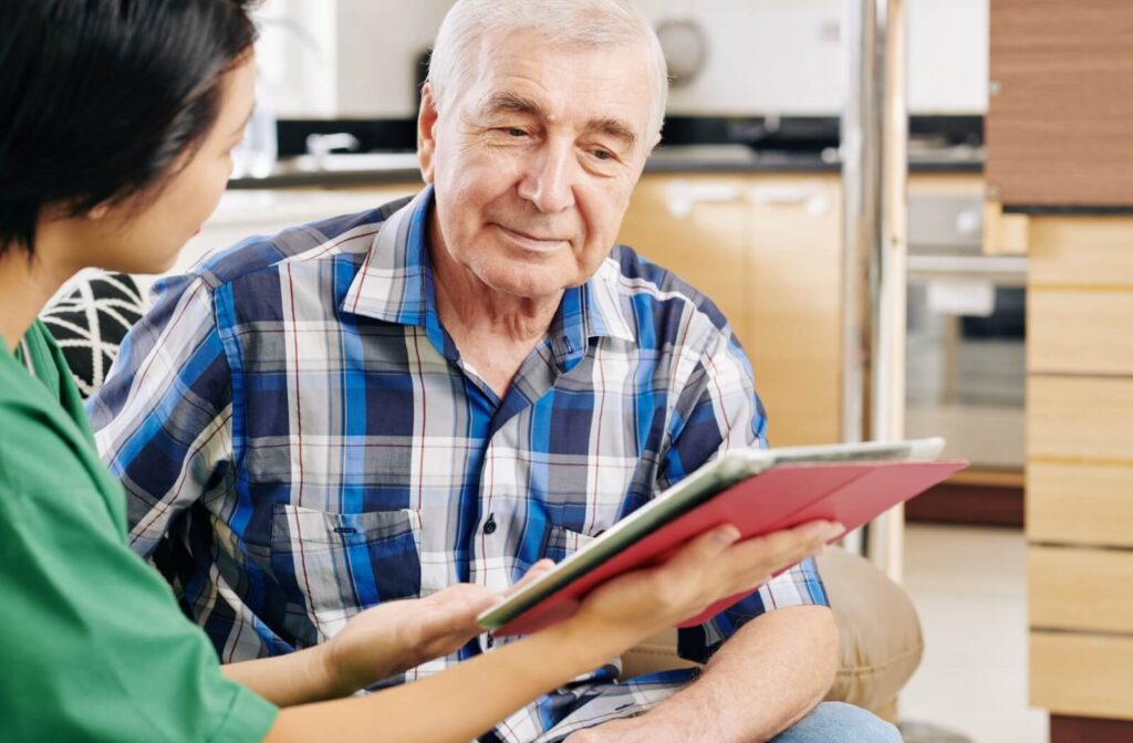 A senior and caregiver sit together looking at a tablet during a reminiscence therapy activity in memory care