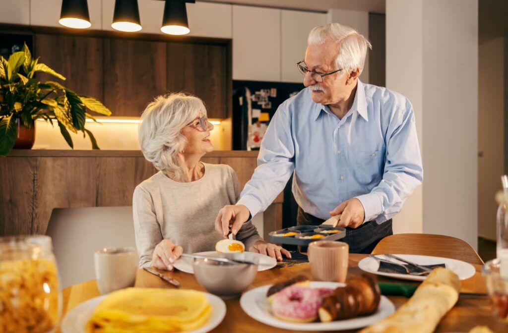 A senior delivers freshly cooked over-easy eggs to their partner as part of a balanced, nutritious breakfast in senior living