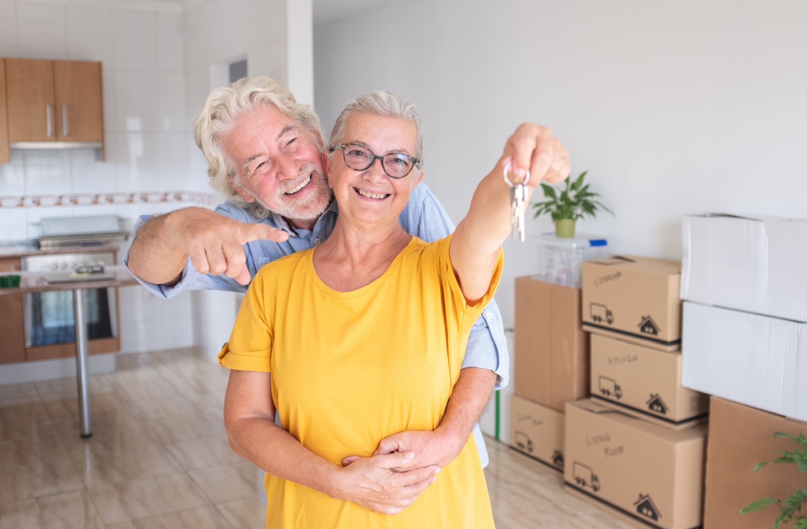 A mature, happy couple holding their keys to their new assisted living apartment.